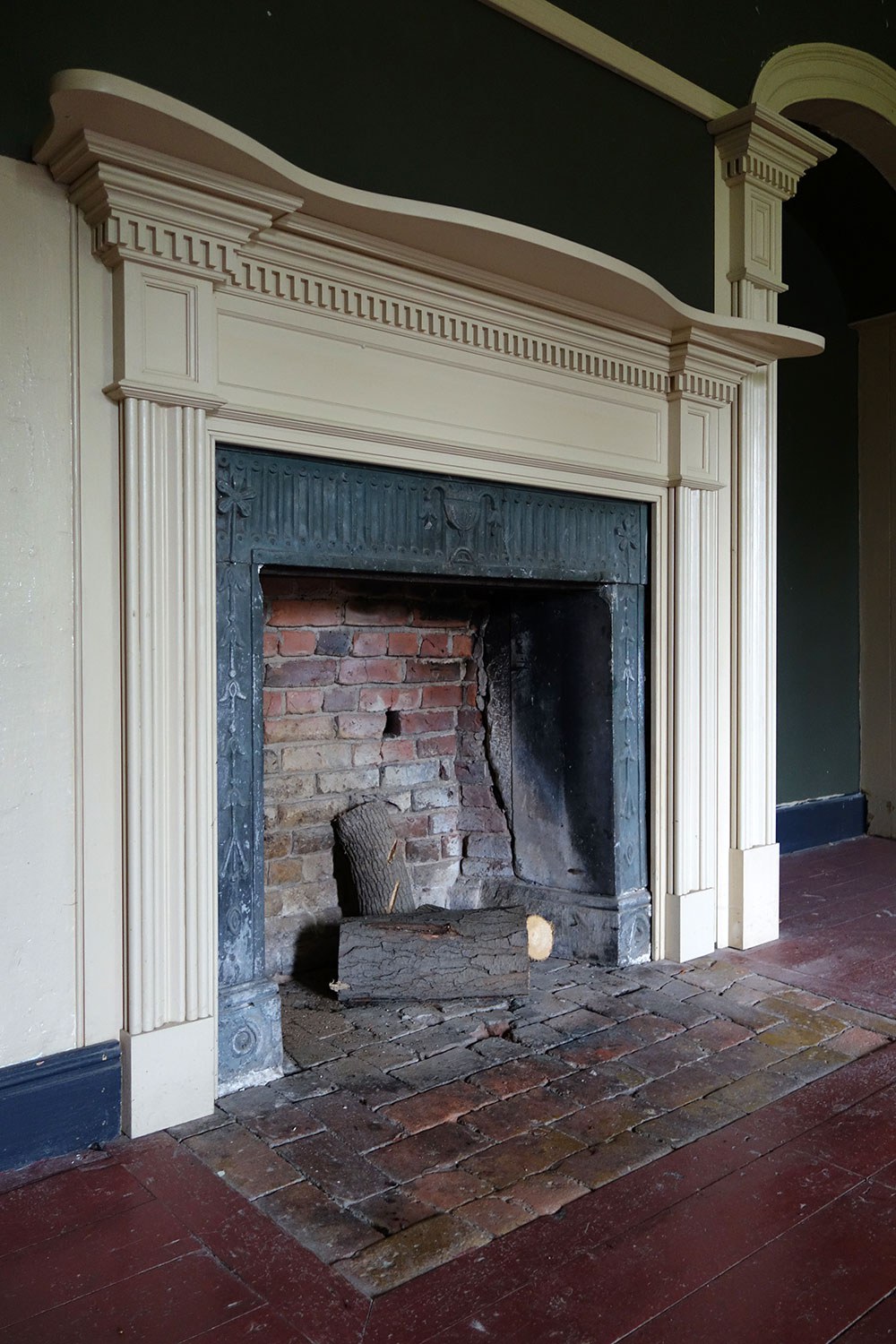 The restored drawing room fireplace has an 1817-era brick hearth and carved stone surround with reproduction painted wood mantel.