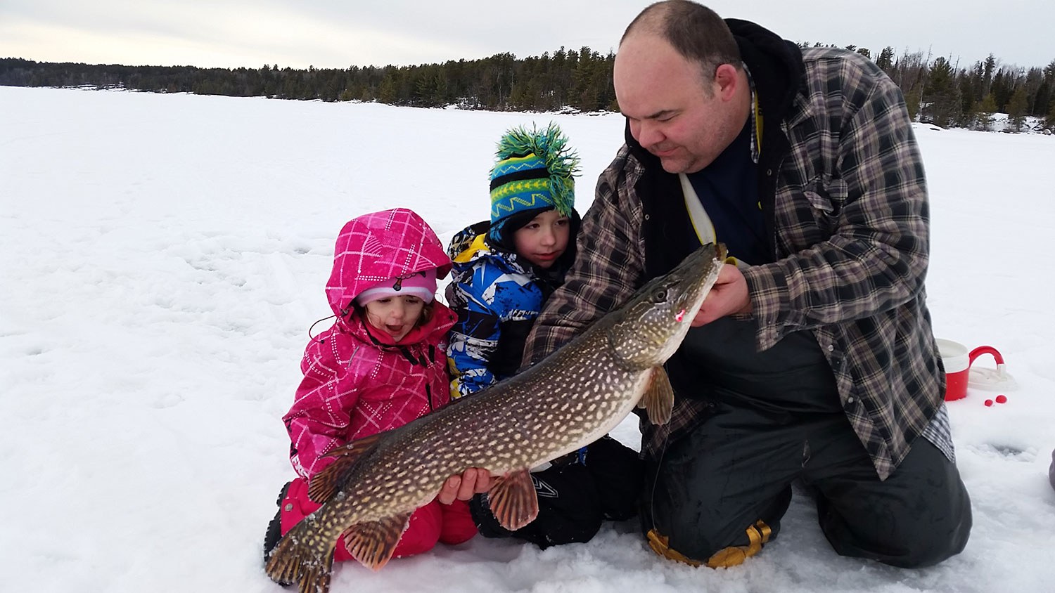 Brian Tucker on Rainy Lake with his two children holding a fish
