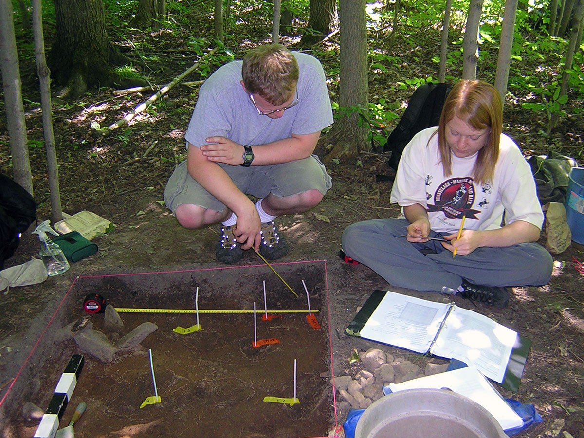 Two field school students record the location of soil stains