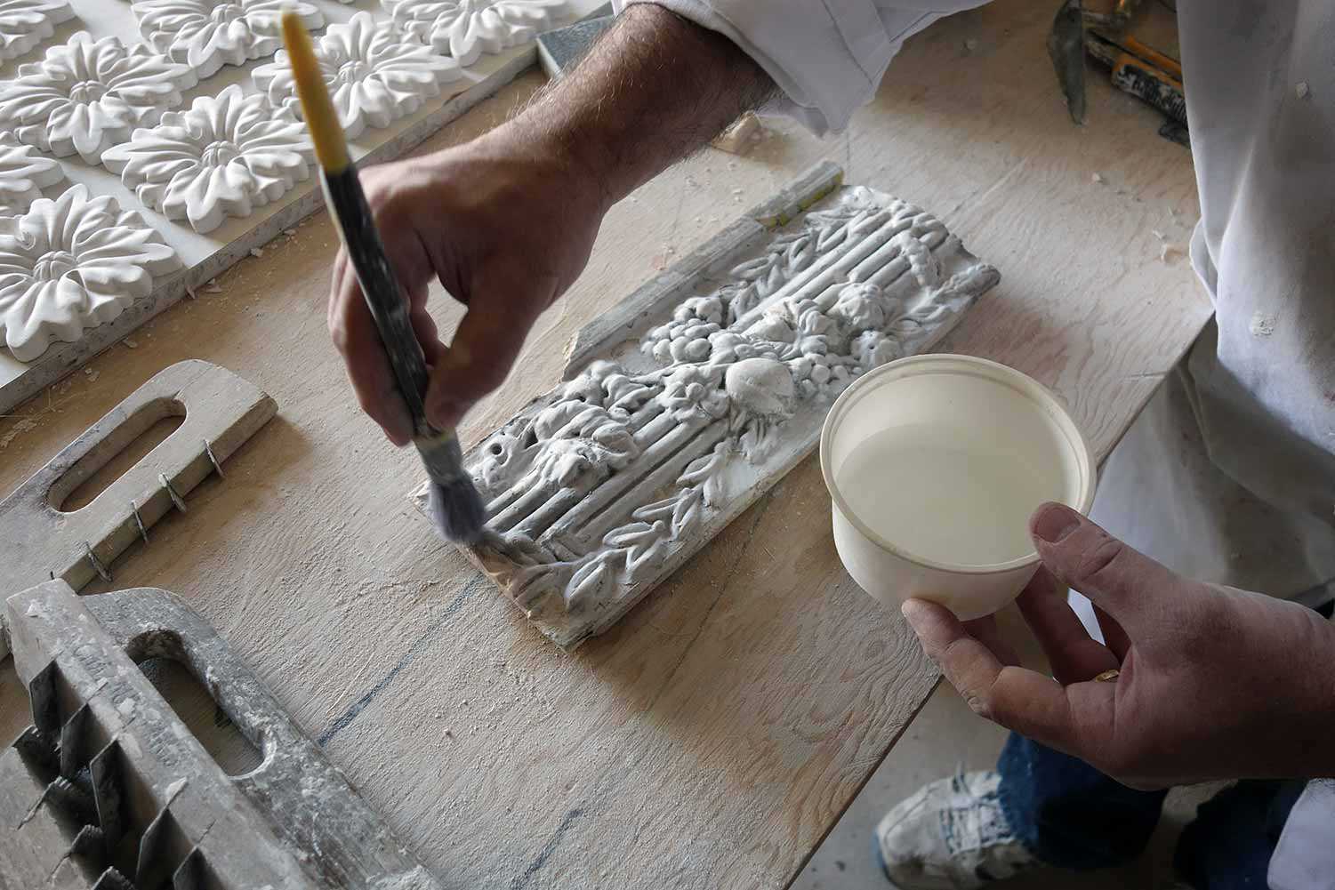 Re-saturating calcimine paint on decorative plaster moulding from 1817. Reproduction rosettes at top left. Homemade traditional plasterer’s tools at bottom left. (Macdonell-Williamson House, Chute-a-Blondeau)