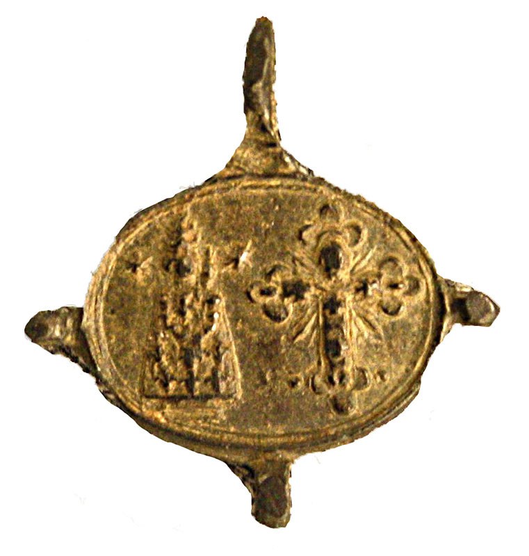 One of the artifacts found in 1977. One side of the medallion depicts Madonna standing beside an ornate cross. A dot at  her left shoulder represents the infant Jesus.